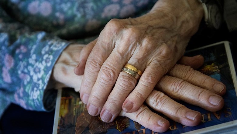 En äldre person händer, som vilar korslagda i knäet.